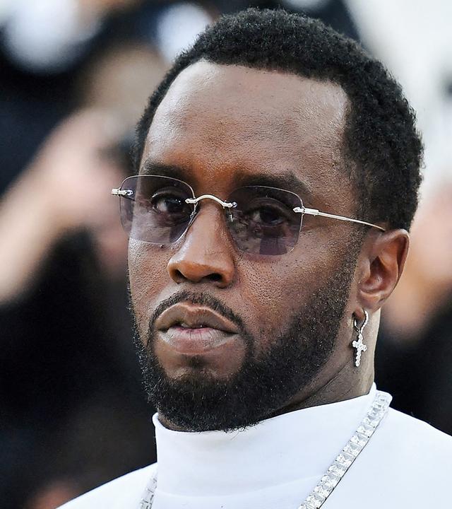 US-Rapper Sean Combs (P. Diddy) steht weiß gekleidet vor Kameras. 