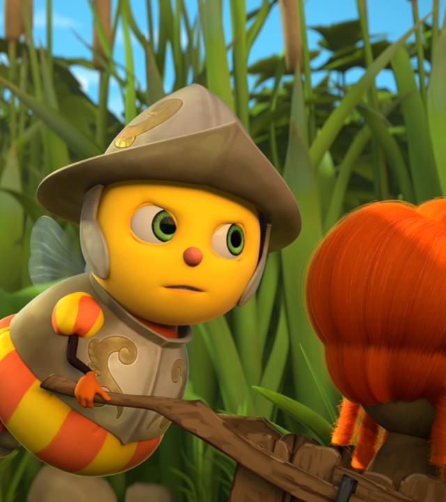 Wächterbiene Brennnessel schiebt eine Schubkarre, auf der eine rote Perücke liegt.