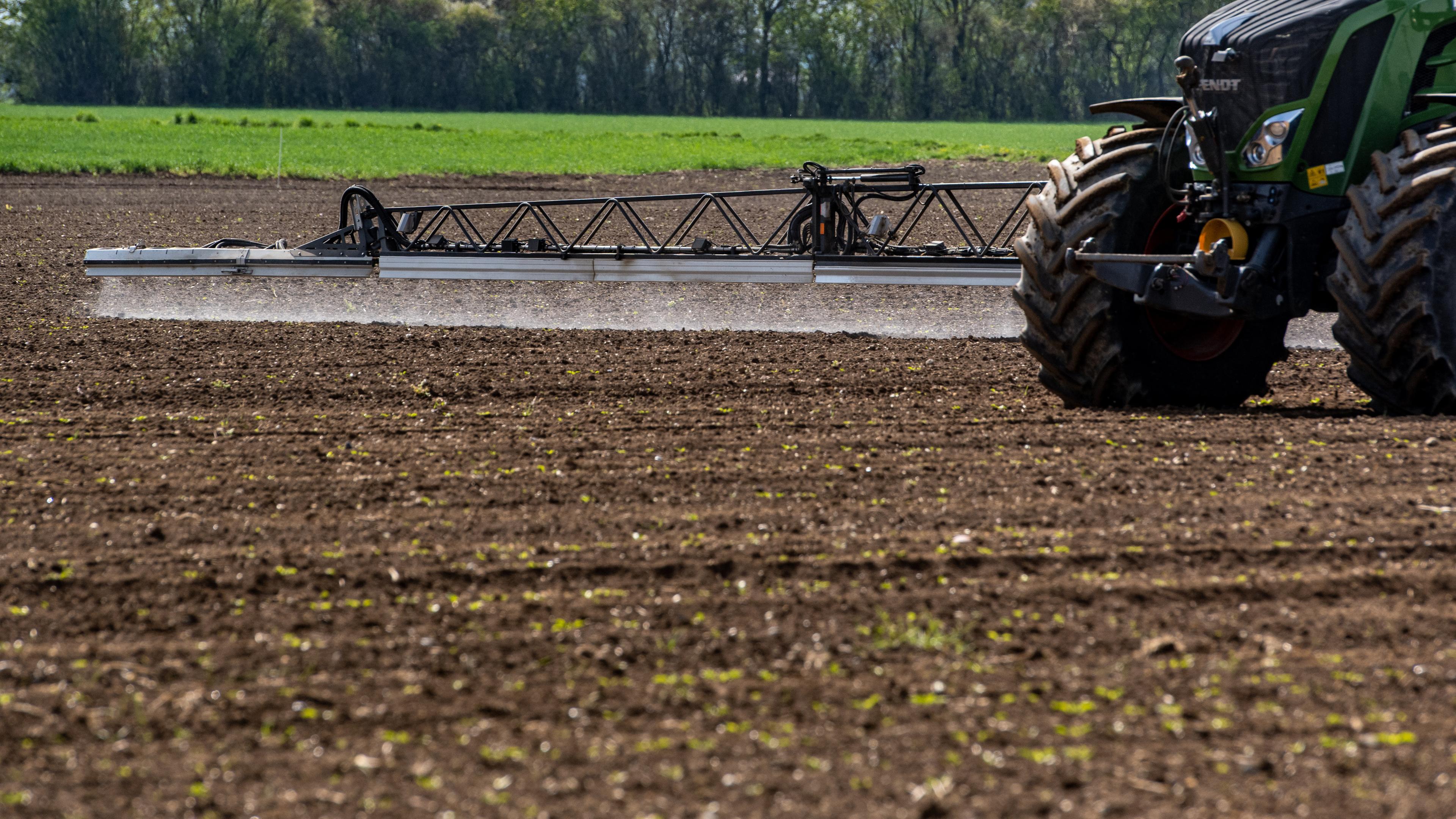 Ein Traktor trägt Pestizide auf ein Feld auf