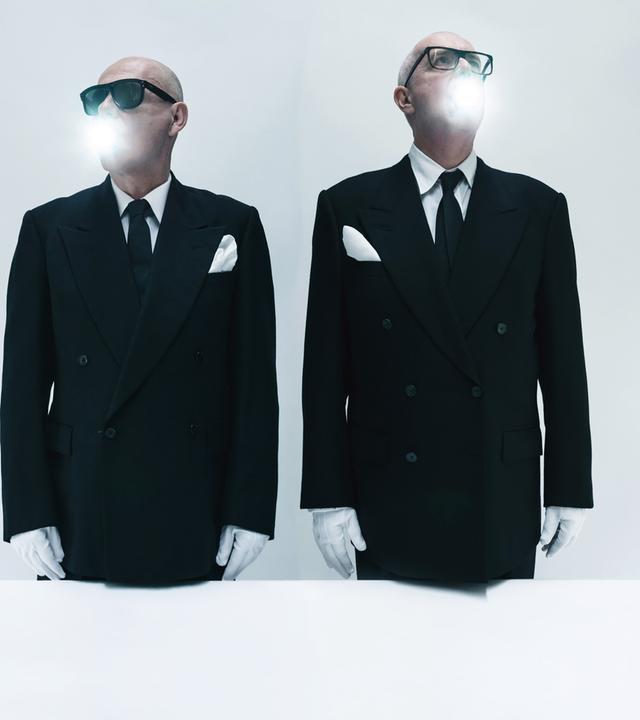 Die Pet Shop Boys stehen in Anzügen und Sonnenbrille vor der Kamera. Sie tragen weiße Handschuhe, aus ihrem Mund kommt weißes Licht.