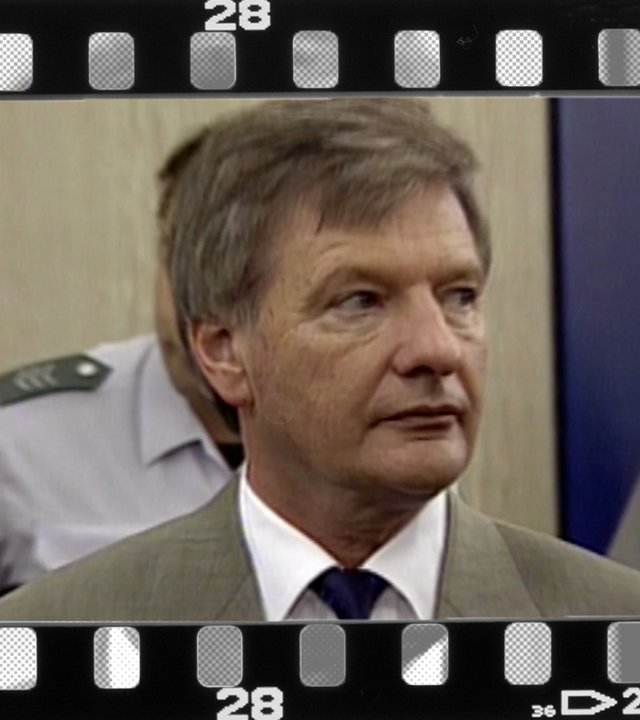 Portrait von Peter Graf im Gerichtssaal. Justizbeamte und Anwälte im Hintergrund.