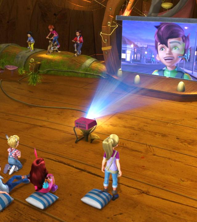 Die Kinder sitzen vor der Leinwand beim Kinoabend, während drei andere Kinder auf Fahrrädern für den Strom strampeln müssen. Auf der Leinwand ist Peter Pan zu sehen.