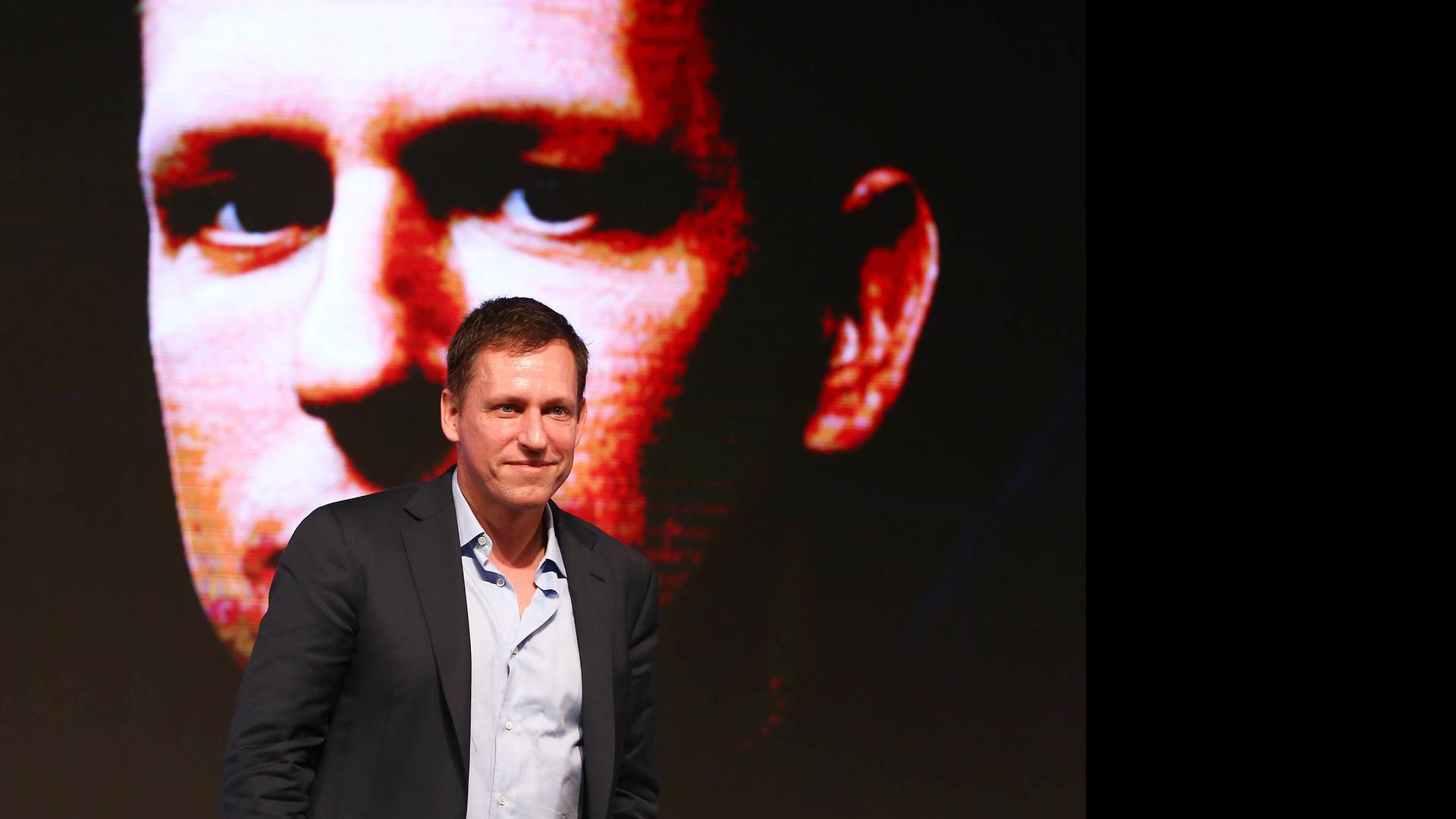 Ein Mann läuft vor einem riesigen an die Wand projizierten Fotos seines eigenen Gesichts.