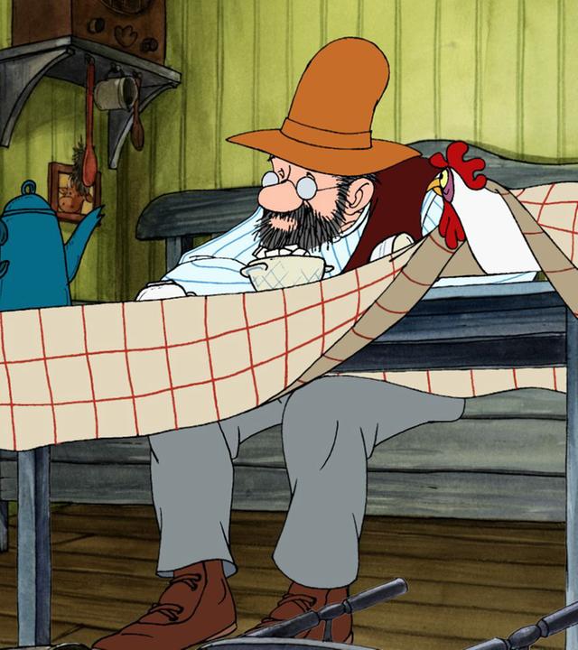 Pettersson sitzt deprimiert am Esstisch in der Küche. Ein Huhn, das unter der Tischdecke sitzt, schaut ihn an.