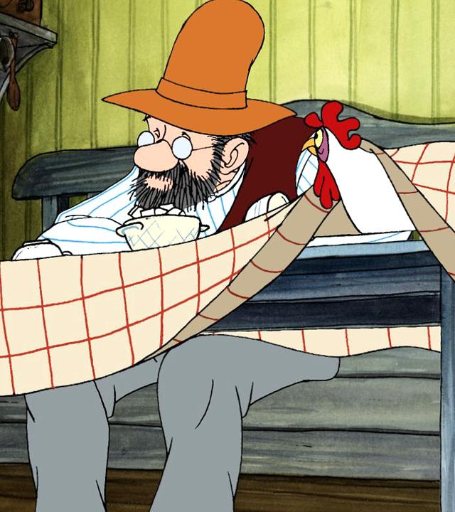 Pettersson sitzt deprimiert am Esstisch in der Küche. Ein Huhn, das unter der Tischdecke sitzt, schaut ihn an.