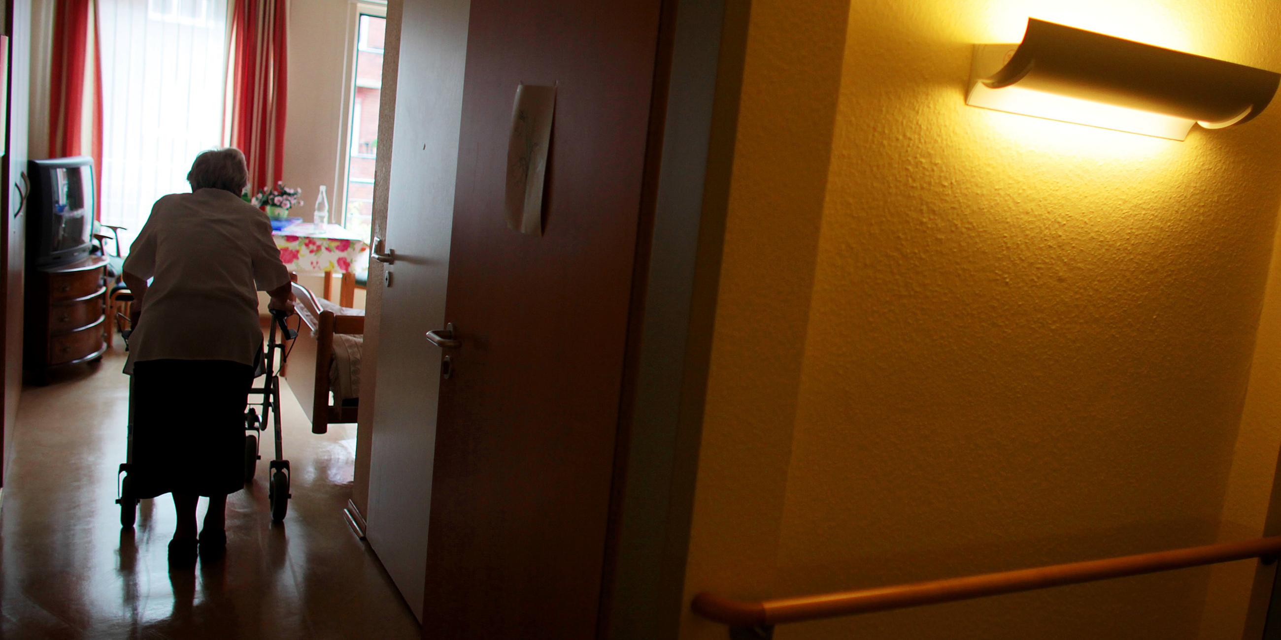 Archiv: Eine Rrau geht in einem Altenheim mit ihrem Rollator in ihr Zimmer