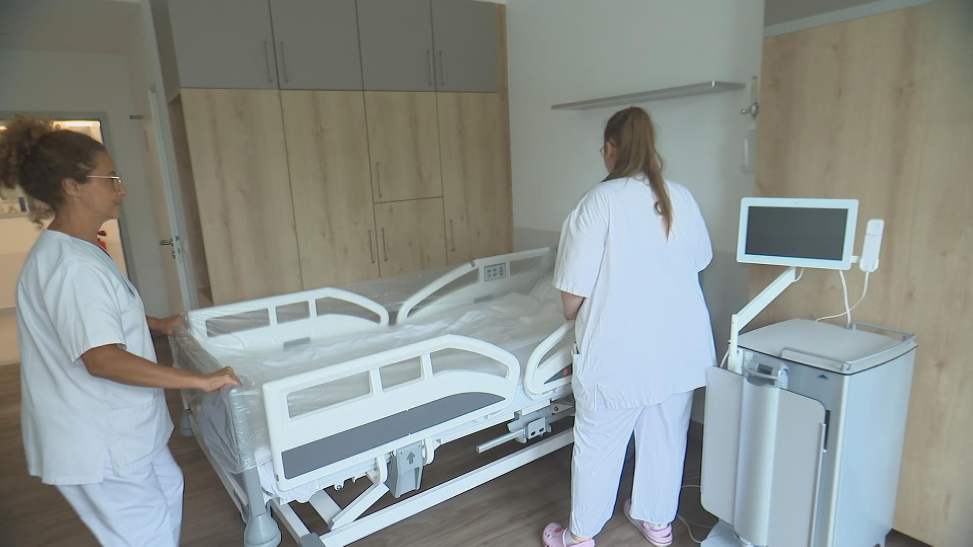 Auf dem Bild sind zwei Pflegerinnen zu sehen, die sich um ein Pflegebett kümmern.