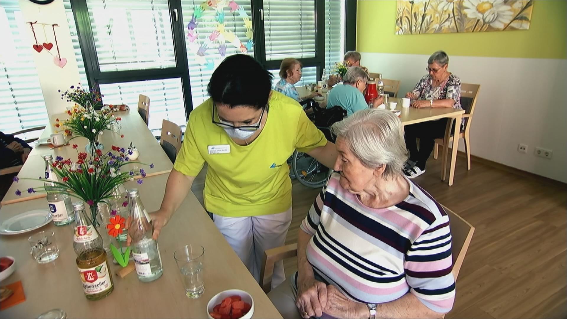 Seniorinnen und Pflegekraft in Aufenthaltsraum im Pflegeheim