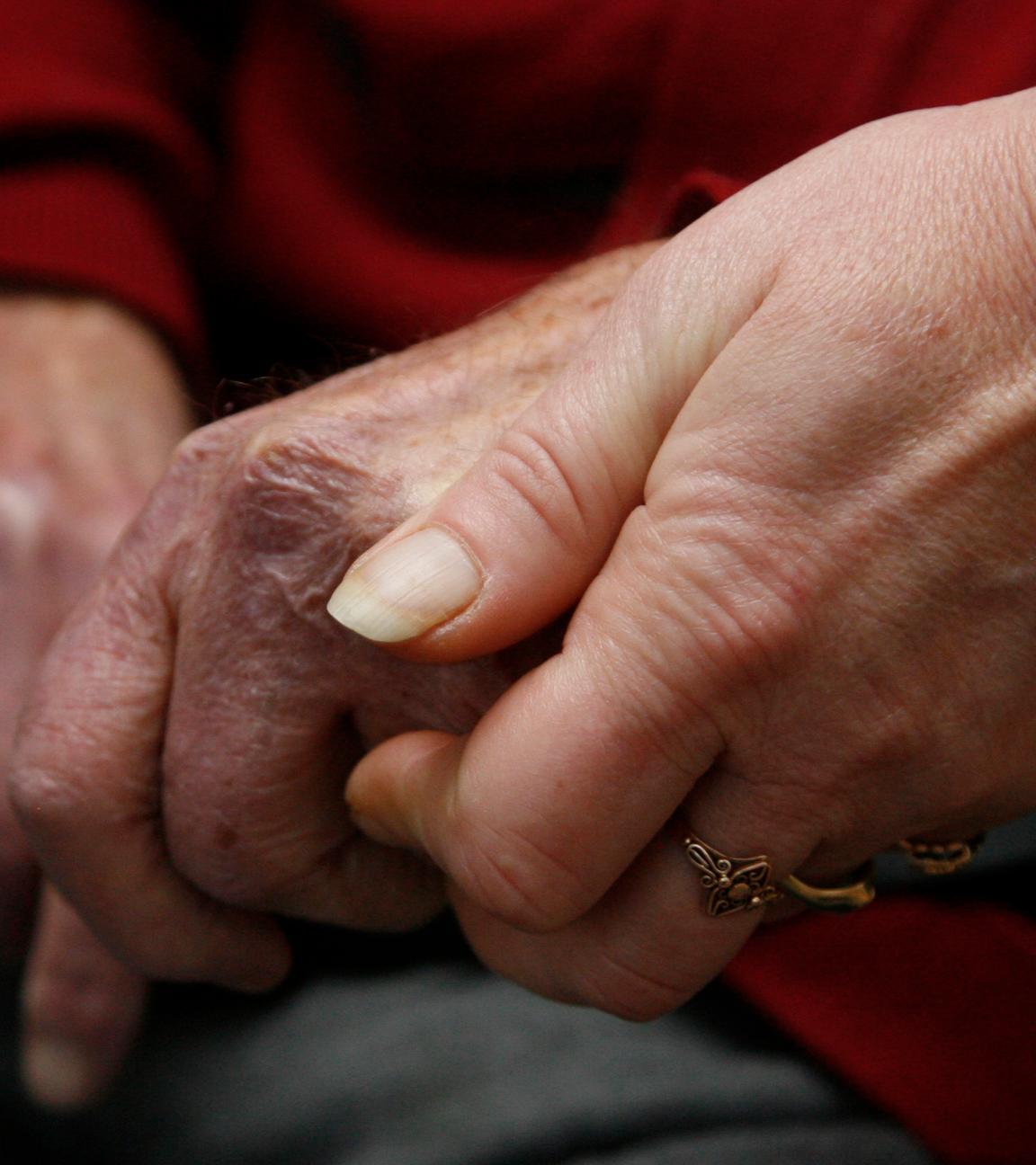Eine jüngere Hand hält eine ältere Hand.