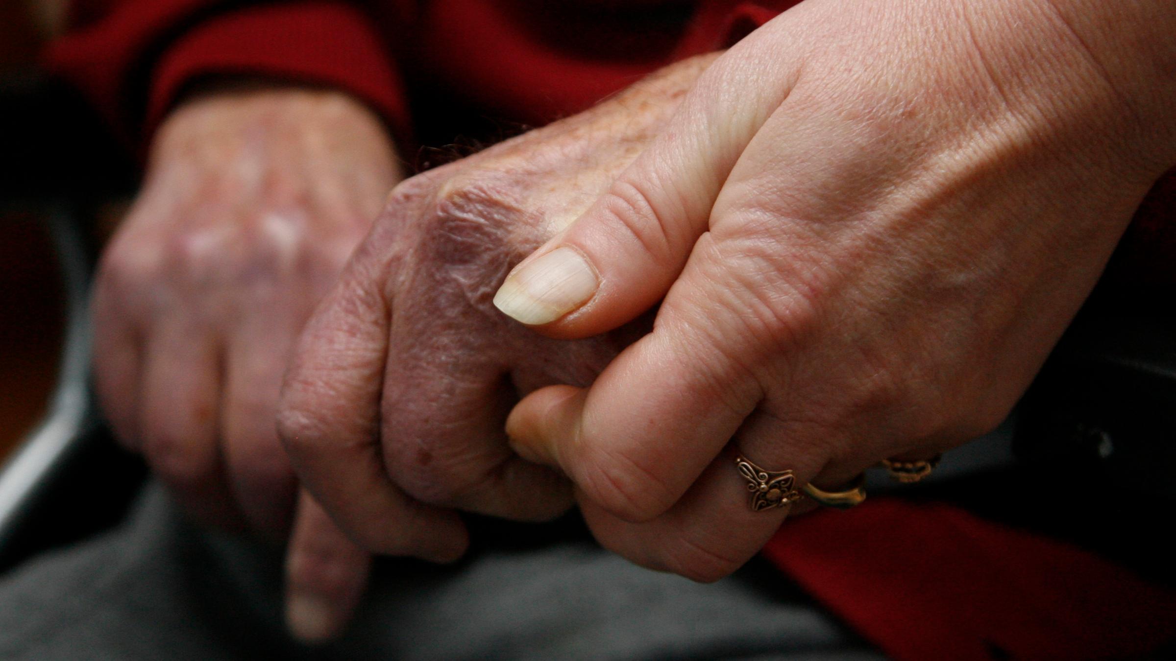 Eine jüngere Hand hält eine ältere Hand.