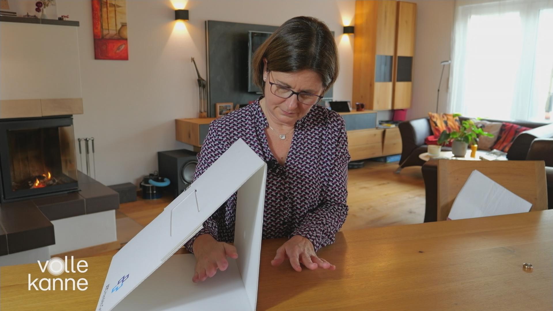 Eine Frau hält eine Hand neben eine Art Karton und die andere Hand (bei der die Extremitäten nicht mehr völlig vorhanden sind) in den Karton