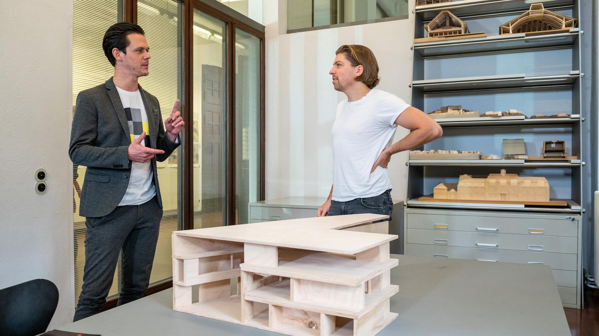 "zdf@bauhaus": Singer-Songwriter Philipp Poisel (rechts) im Interview mit Moderator Jo Schück (links). Im Hintergrund stehen Holz-Modelle im Regal. Vorne links ist ein Bildschirm, auf dem Philipp Poisel zu sehen ist.