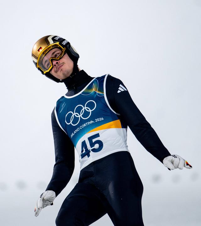 Der deutsche Skispringer Philipp Raimund blickt nach seinem Sprung bei den Olympischen Winterspielen 2026 in Predazzo enttäuscht in die Zuschauermengen