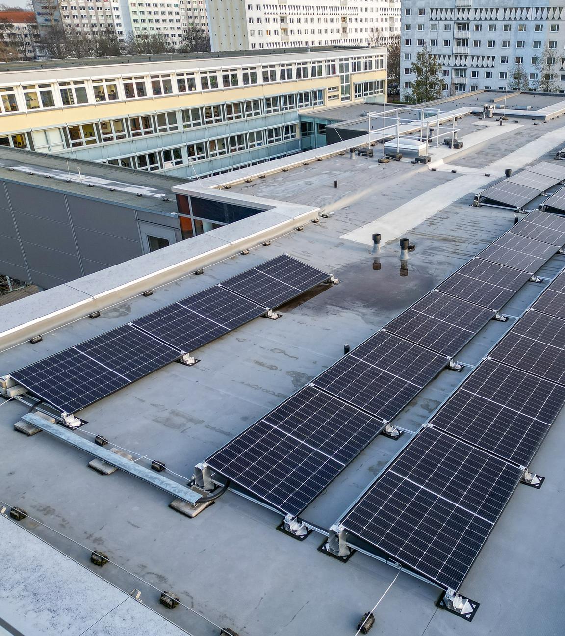 Mehrere Solaranlagen auf dem Flachdach eines Gebäudekomplexes.