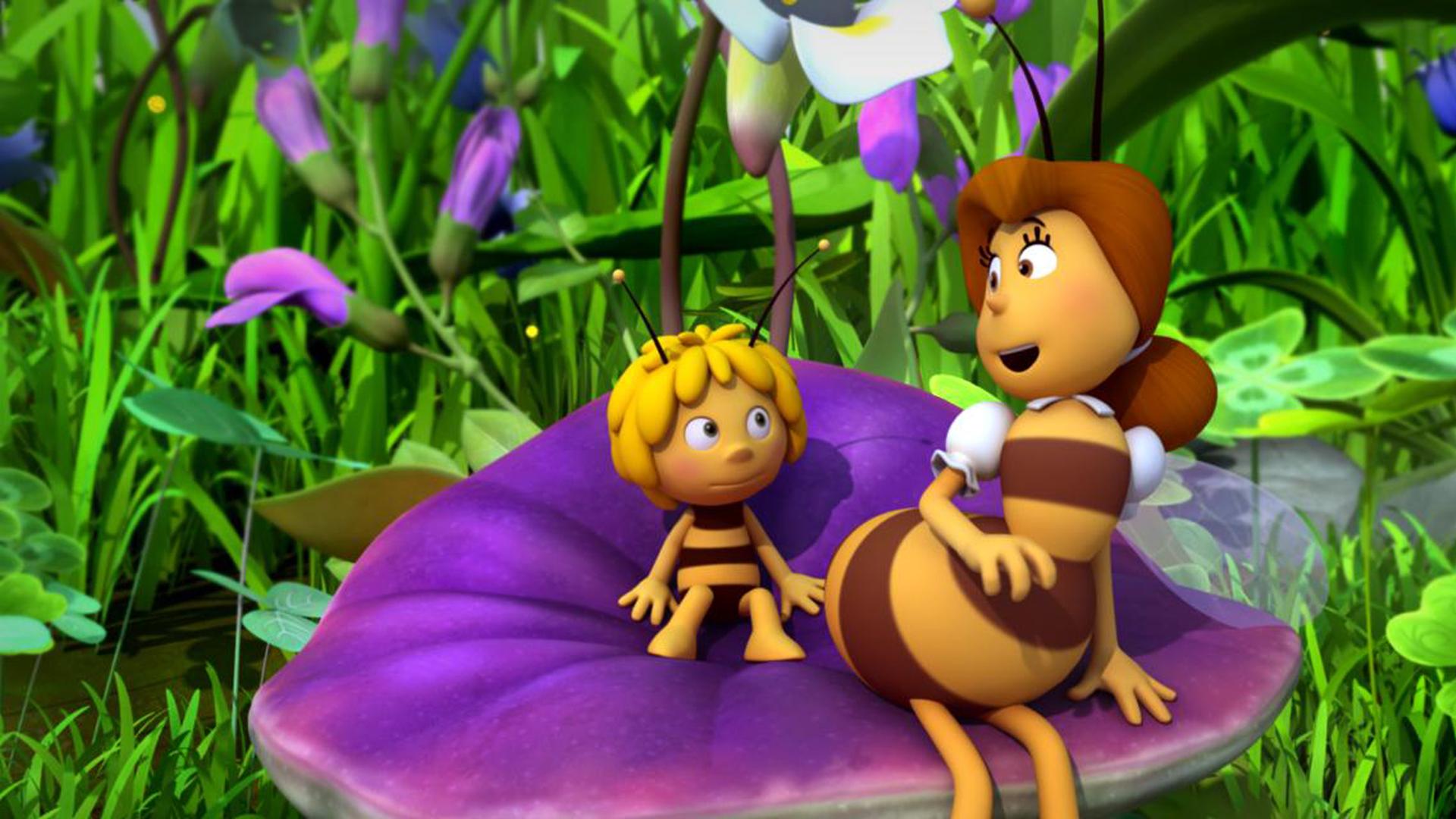 Frau Kassandra und Maja sitzen auf einer lilafarbenen Blume.