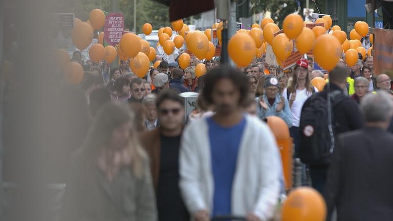 "Pillen, Pulver, Wunderheiler": Bild einer Demo. Es ist eine Menschenmenge mit zahlreichen orangefarbenen Ballons zu sehen.
