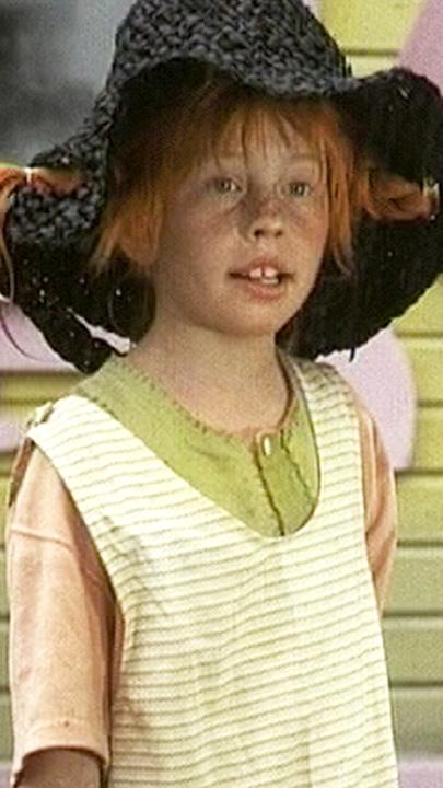 Pippi Langstrumpf trägt auf dem Kopf einen schwarzen Hut, aus dem links und rechts ihre roten Zöpfe hängen.