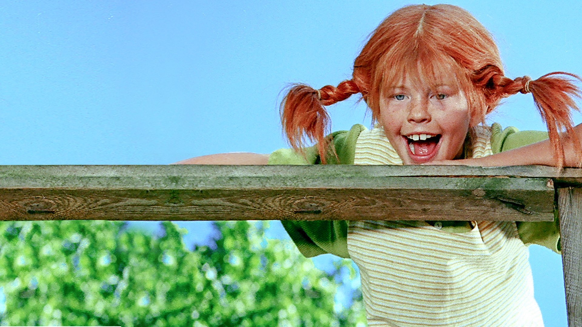 Pippi Langstrumpf schaut ganz frech und stützt sich auf das Holzgeländer des Schiffes.