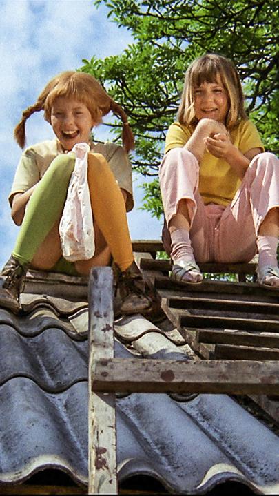 Pippi Langstrumpf sitzt mit Annika und Tommy auf dem Dach.
