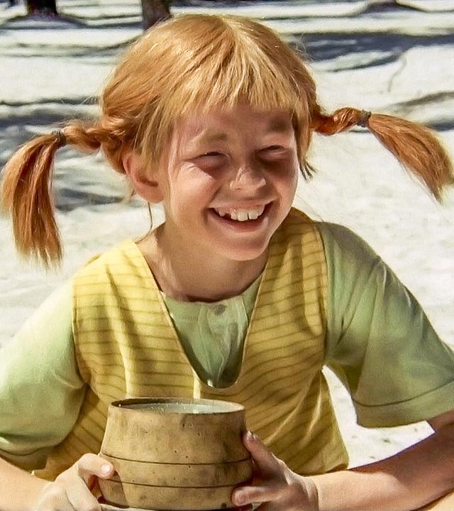 Pippi Langstrumpf sitzt auf einer Insel im Sand und hält ein kleines Pulverfaß in den Händen.