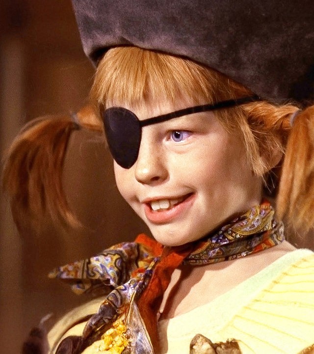 Pippi trägt einen Piratenhut und eine schwarze Augenklappe. Vor sich hält sie einen Spieß mit Brot, Hühnchen und einer grünen Paprika.