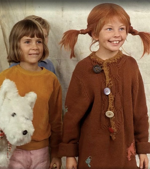 Pippi und Annika schauen begeistert einer Vorführung zu. Hinter den beiden steht Tommi ganz versteckt und Annika hat einen weißen Stoffhund unterm Arm