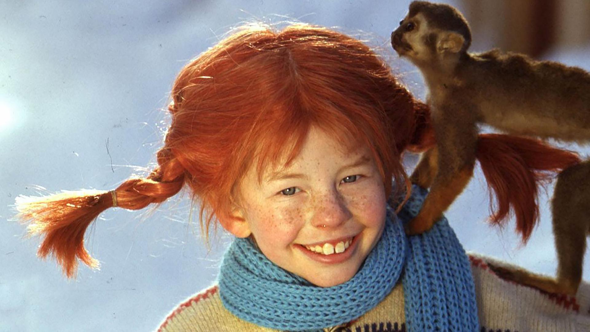 Pippi Langstrumpf steht im Schnee mit ihrem Äffchen Herr Nielson auf dem Arm.