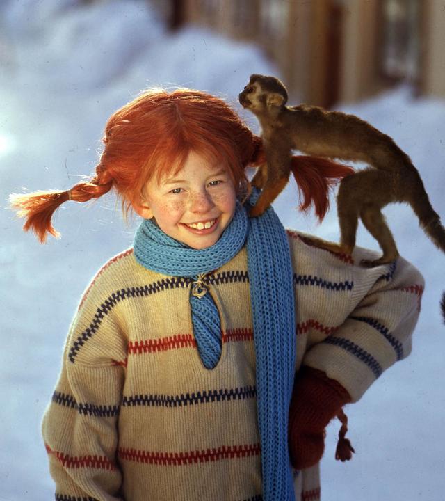 Pippi Langstrumpf steht im Schnee mit ihrem Äffchen Herr Nielson auf dem Arm.