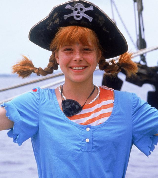 "Pippi Langstrumpfs neueste Streiche": Pippi Langstrumpf (Tami Erin) steht auf einem Schiff und lächelt. Sie trägt einen Piratenhut, einen Dreizack mit einem Totenkopf darauf.