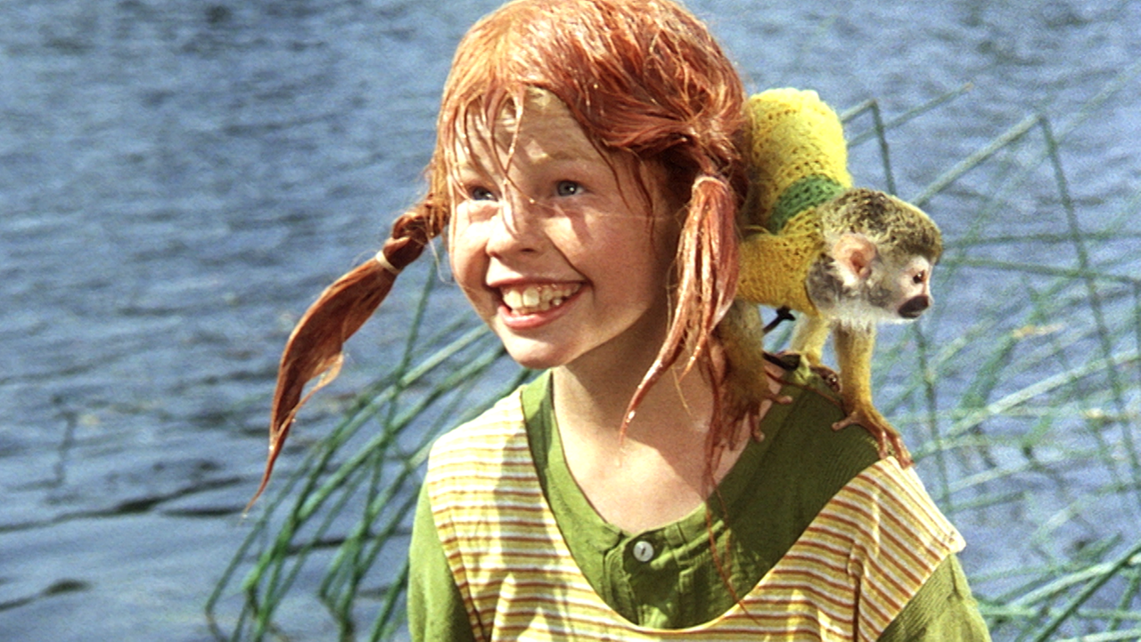 Pippi steht nass und grinsend vor einem See. Auf ihrer Schulter sitzt das Totenkopfäffchen Herr Nilsson.