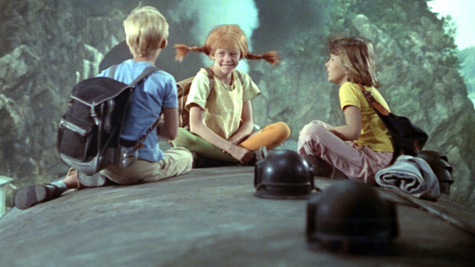 Pippi, Annika und Tommy sitzen auf dem Dach eines fahrenden Zugs.