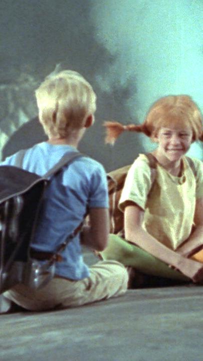 Pippi (Mitte), Annika (rechts) und Tommy (links) sitzen auf dem Dach eines fahrenden Zugs.