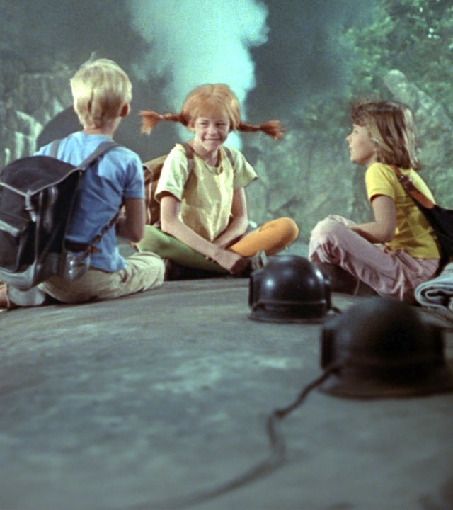 Pippi, Annika und Tommy sitzen auf dem Dach eines fahrenden Zugs.