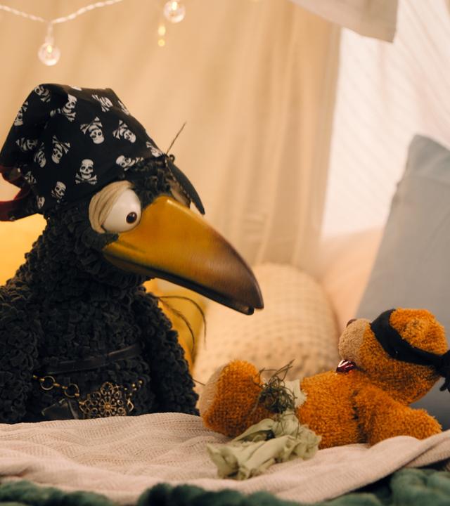  Rudi hockt in der Kuschelecke und schaut auf seinen Teddy. Beide sind als Piraten verkleidet.