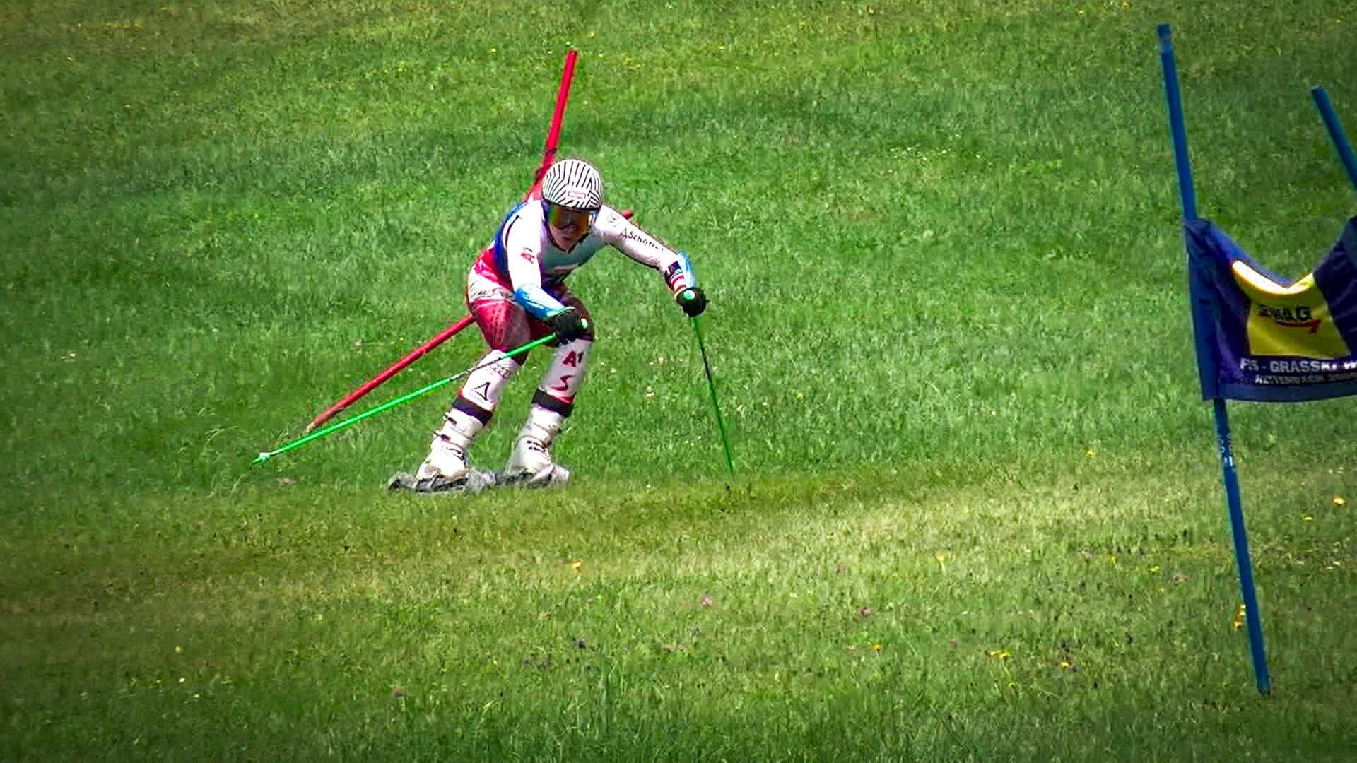 Skifahrer beim Slalom auf einer grünen Wiese