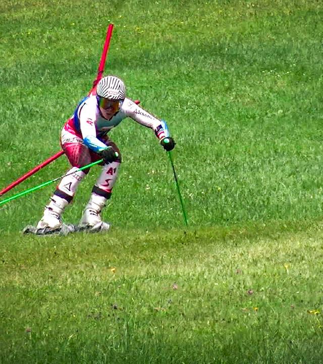 Skifahrer beim Slalom auf einer grünen Wiese