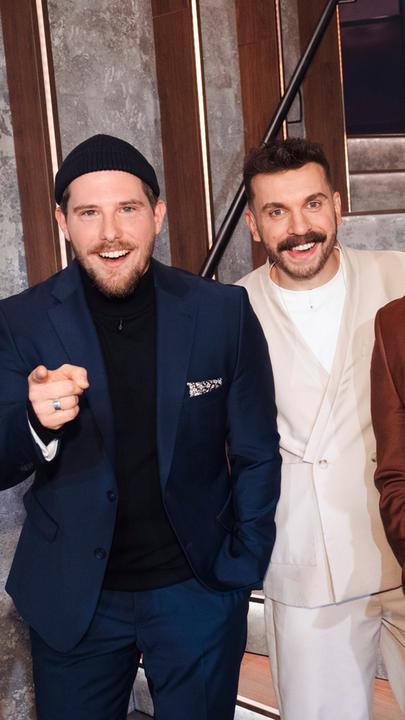 Dennis und Benni Wolter gemeinsam mit Moderator Edin Hasanovic vor der Treppe im Studio von "Edins Neo Night".