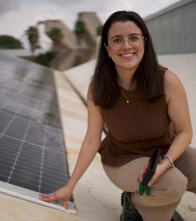 "plan b: City Vibes - wie kühlen wir unsere Städte ab?": Die junge Ingenieurin María de la Paz Montero Gutiérrez sitzt in der Hocke neben einem Aufbau mit Solarzellen und schaut lächelnd in die Kamera.