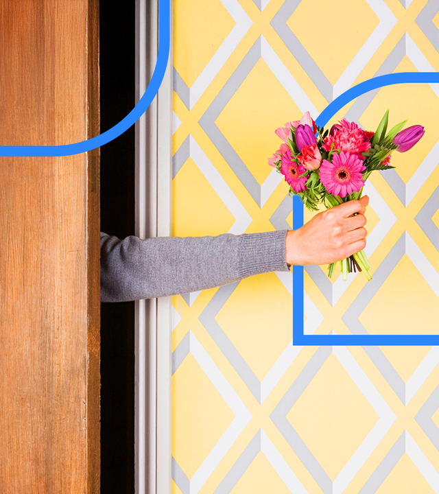 Eine ausgestreckte Hand mit einem Blumenstrauß wird durch einen Türspalt