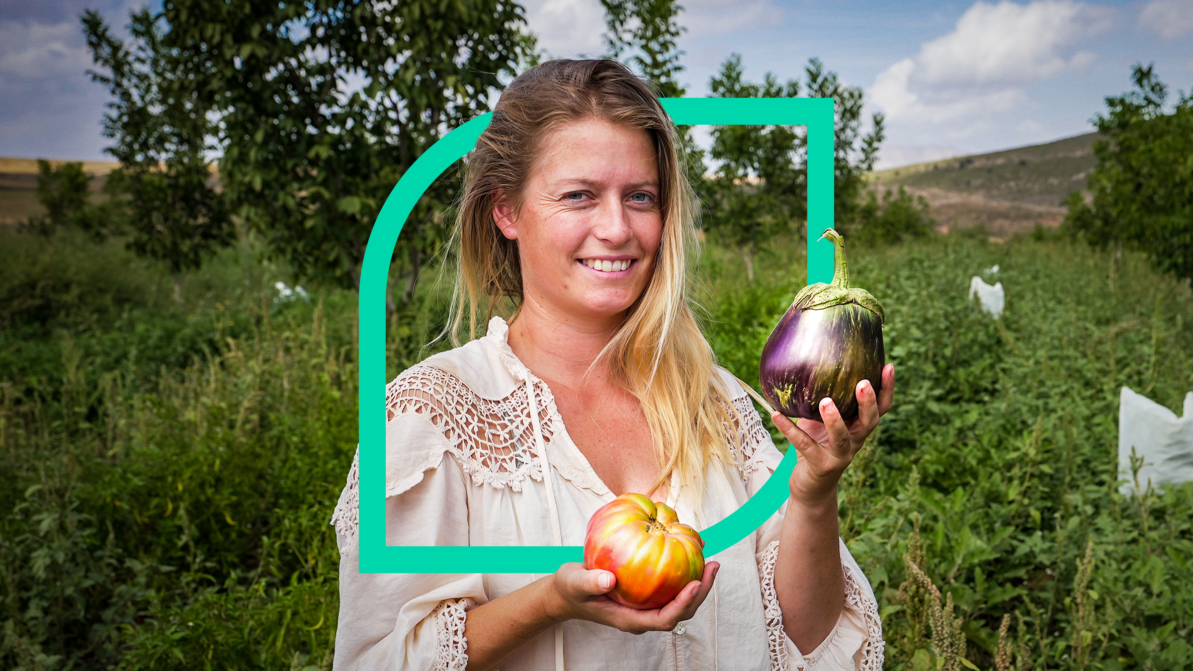 Yanniek, die Leiterin der Regeneration Academy, steht mit Gemüse in den Händen in ihrem Gemüsegarten und lächelt.