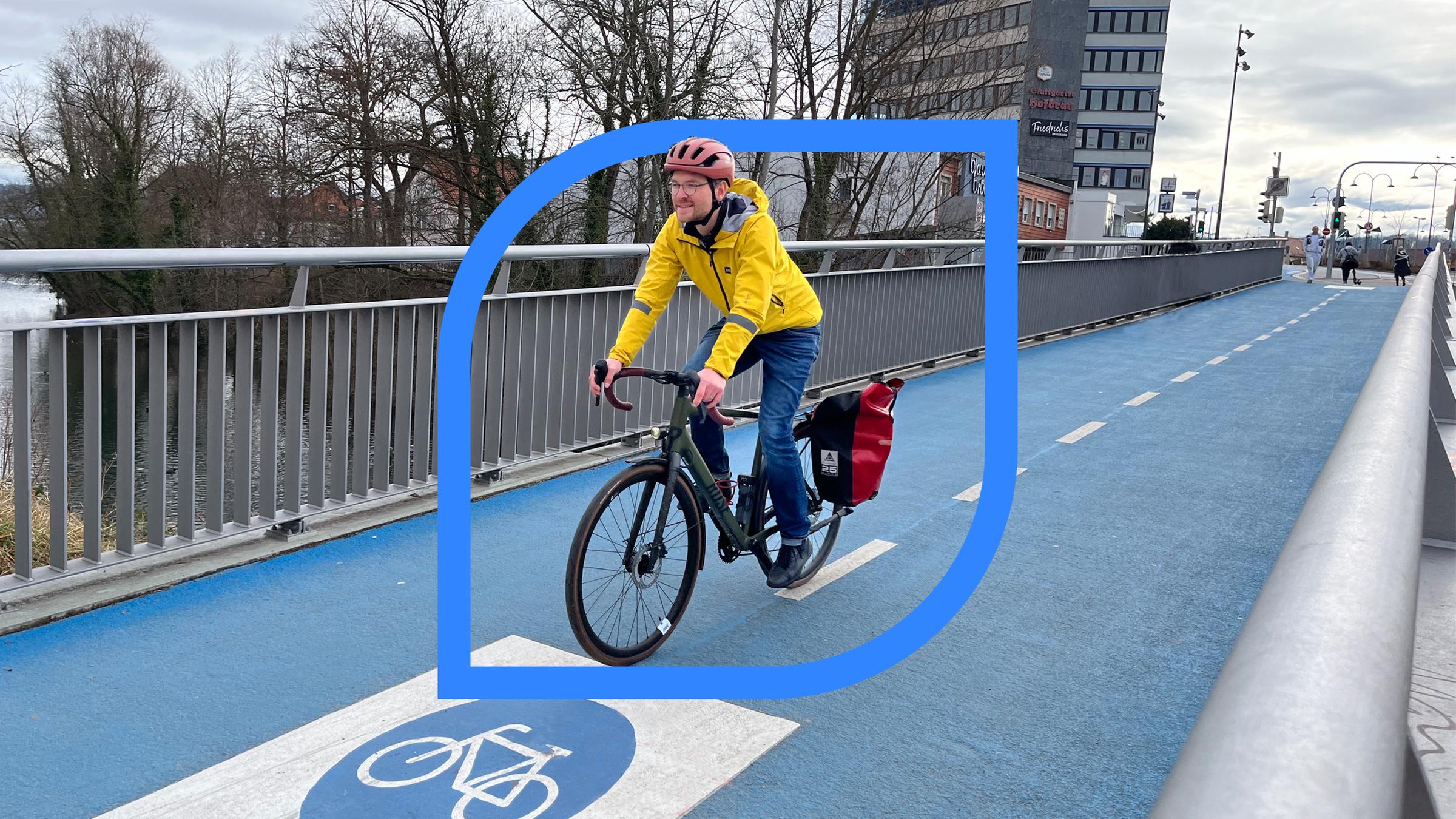 Ein Fahrradfahrer mit Helm und gelber Jacke auf einer Fahrradstraße.