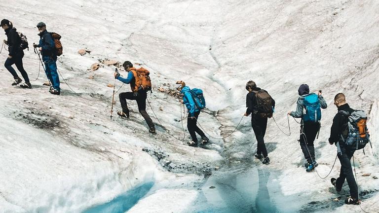 Blick von oben auf eine Wandergruppe, die über den Aletschgletscher in der Schweiz läuft