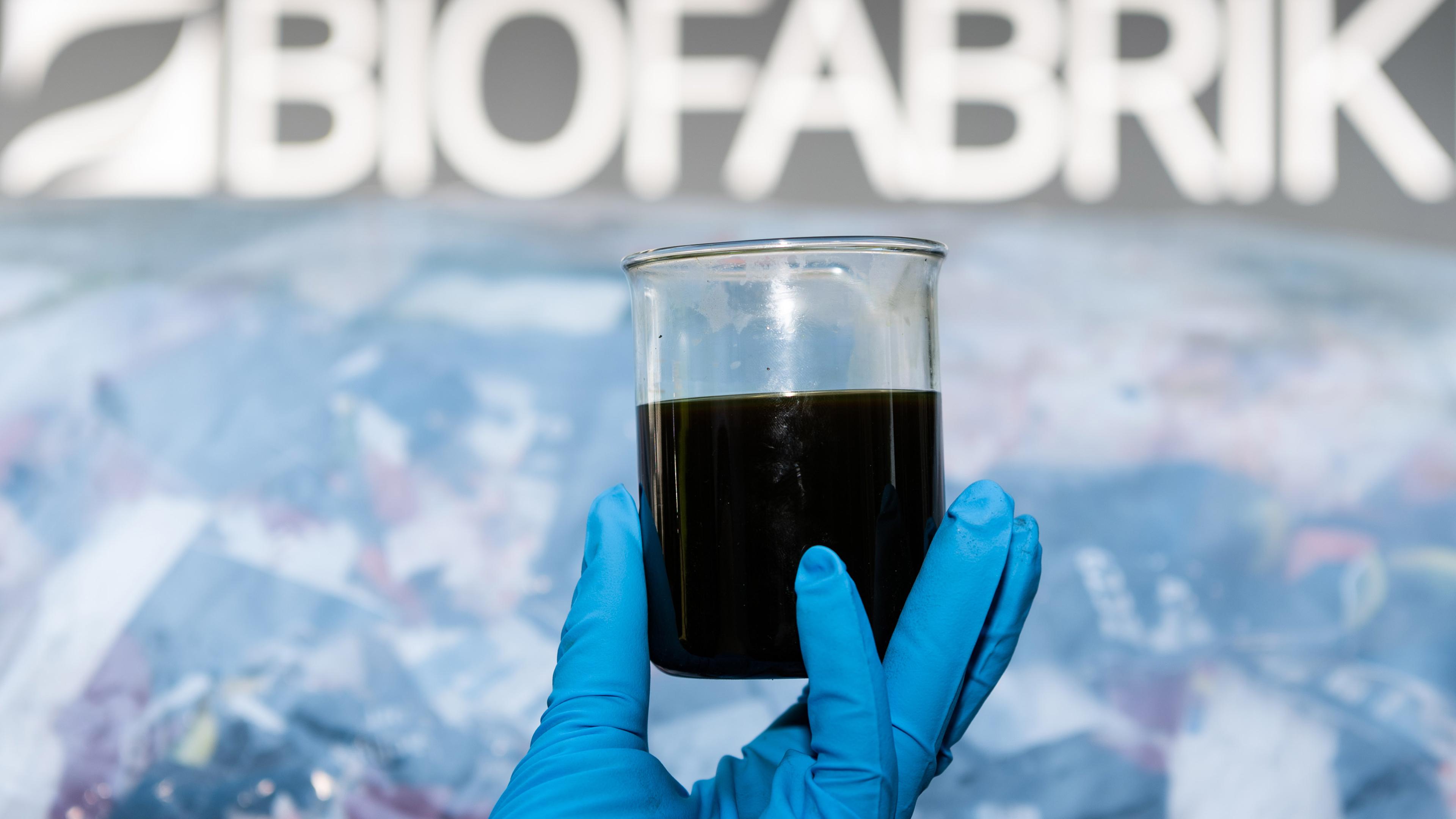 In einem Glaskolben wird Biosprit hochgehalten - produziert aus Plastikmüll