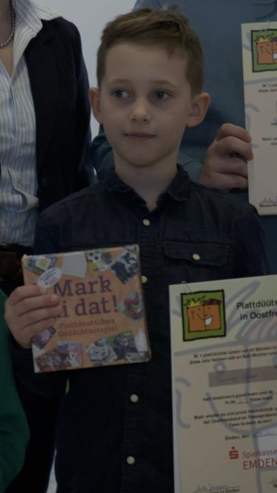 Schüler halten eine Ukrunde des Plattdeutsch-Vorlesewettbewerbs in ihren Händen