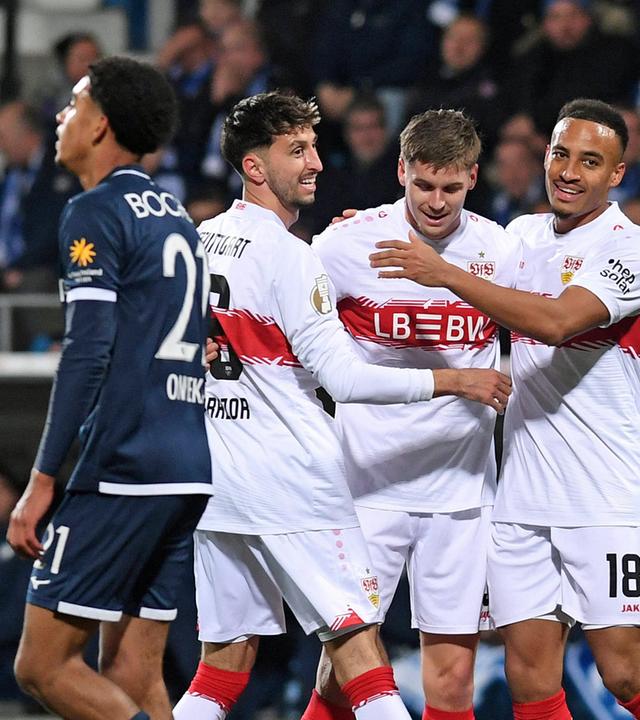 DFB-Pokal: Stuttgarter Spieler jubeln nach einem Treffer zusammen. Ein Bochumer Spieler läuft bedröppelt im Vordergrund vorbei (Unschärfe).