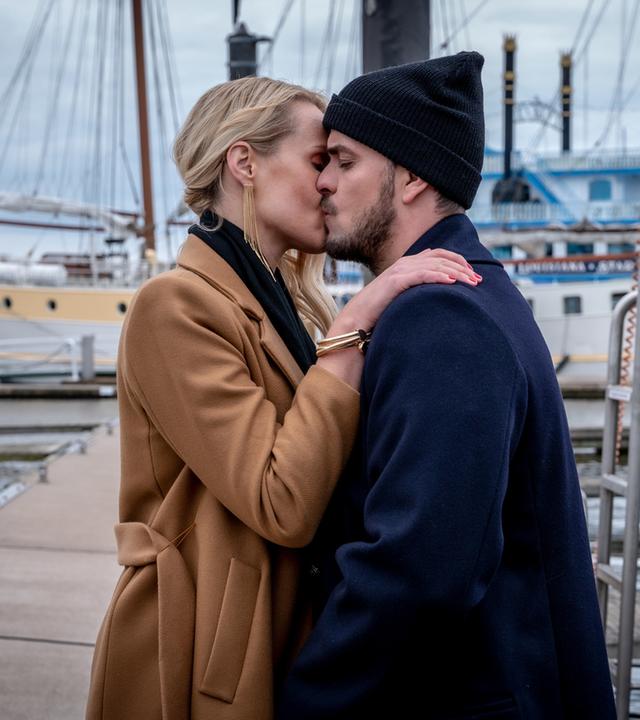 "Notruf Hafenkante - Pokerprinzessin": Kris Freiberg (Marc Barthel) und Lena Marx (Anna Hofbauer) stehen sich im Hamburger Hafen gegenüber. Lena hat ihre recht Hand auf Kris' linker Schulter liegen. Sie küssen sich.