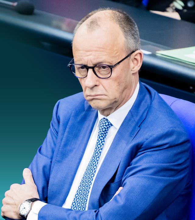 Friedrich Merz, im Bundestag sitzend. Er sieht unzufrieden aus.