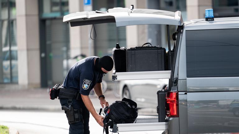 Ein Sprengstoffentschärfer der Technischen Sondergruppe (TSG) des Bayerischen Landeskriminalamts steht neben einem Einsatzfahrzeug im Bahnhofsbereich.