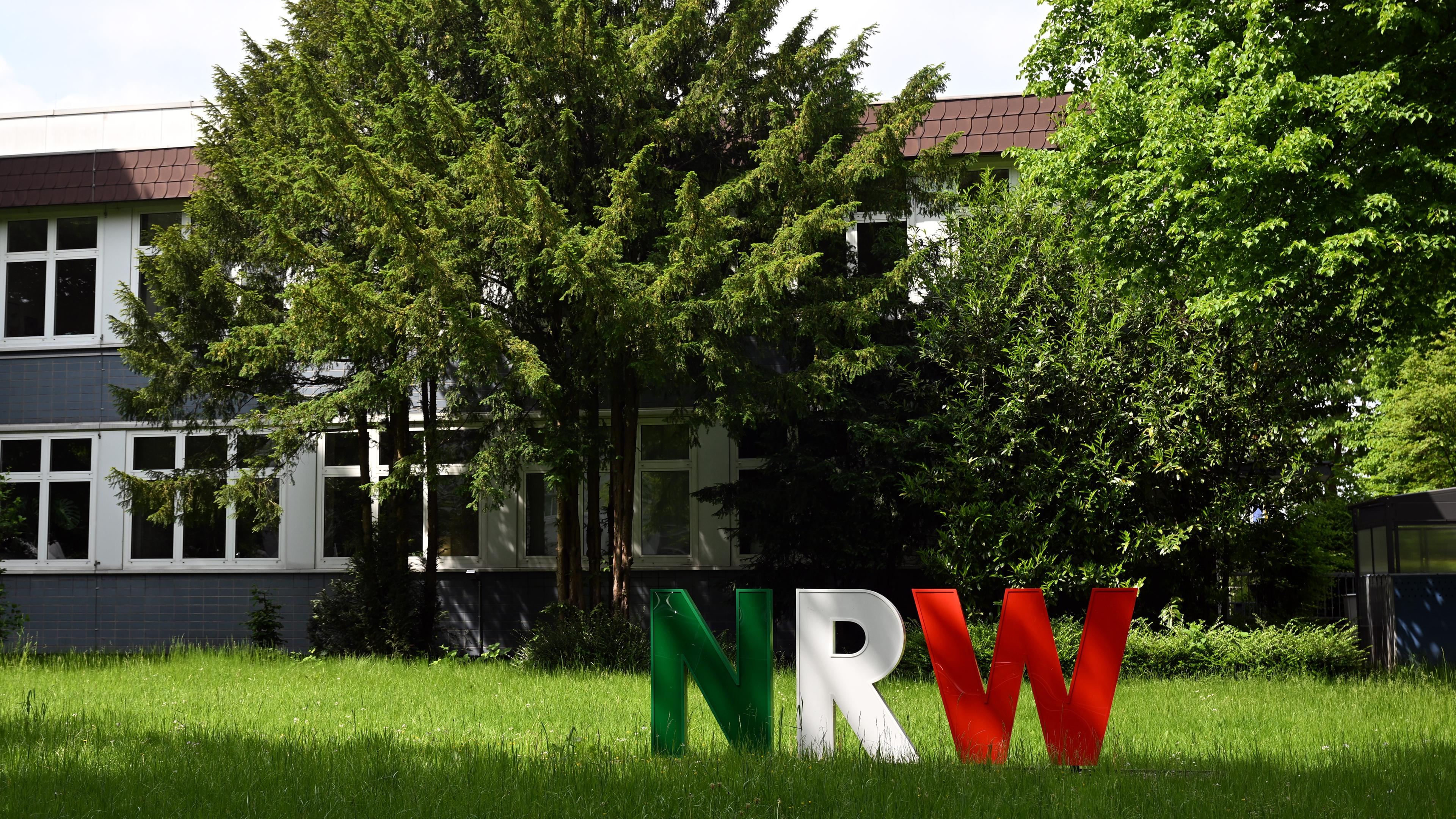 Nordrhein-Westfalen, Gelsenkirchen: Die Buchstaben "NRW" stehen in den Landesfarben von Nordrhein-Westfalen vor der Zentralverwaltung der Hochschule für Polizei und öffentliche Verwaltung Nordrhein-Westfalen auf dem Rasen.