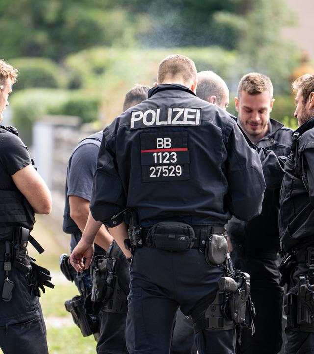 Polizisten koordinieren die Such in einem Wohngebiet in Teltow nach einem Wildtier. 